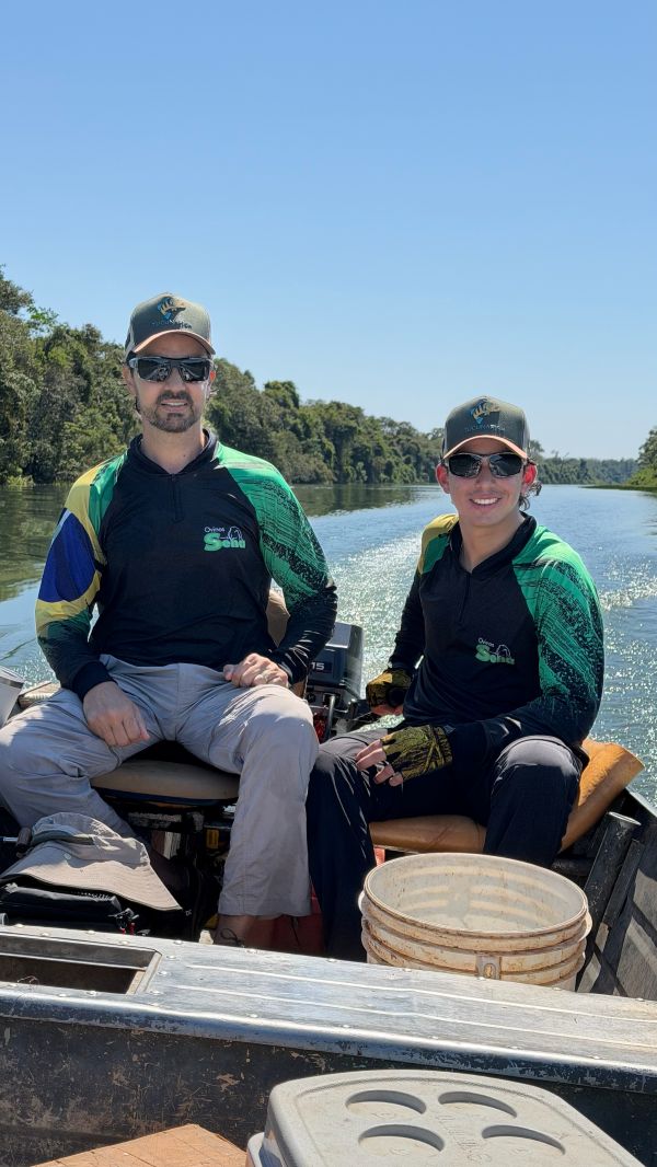 Pai e filho no barco vestindo camisas de pesca TucunaFish personalizadas iguais, com logo