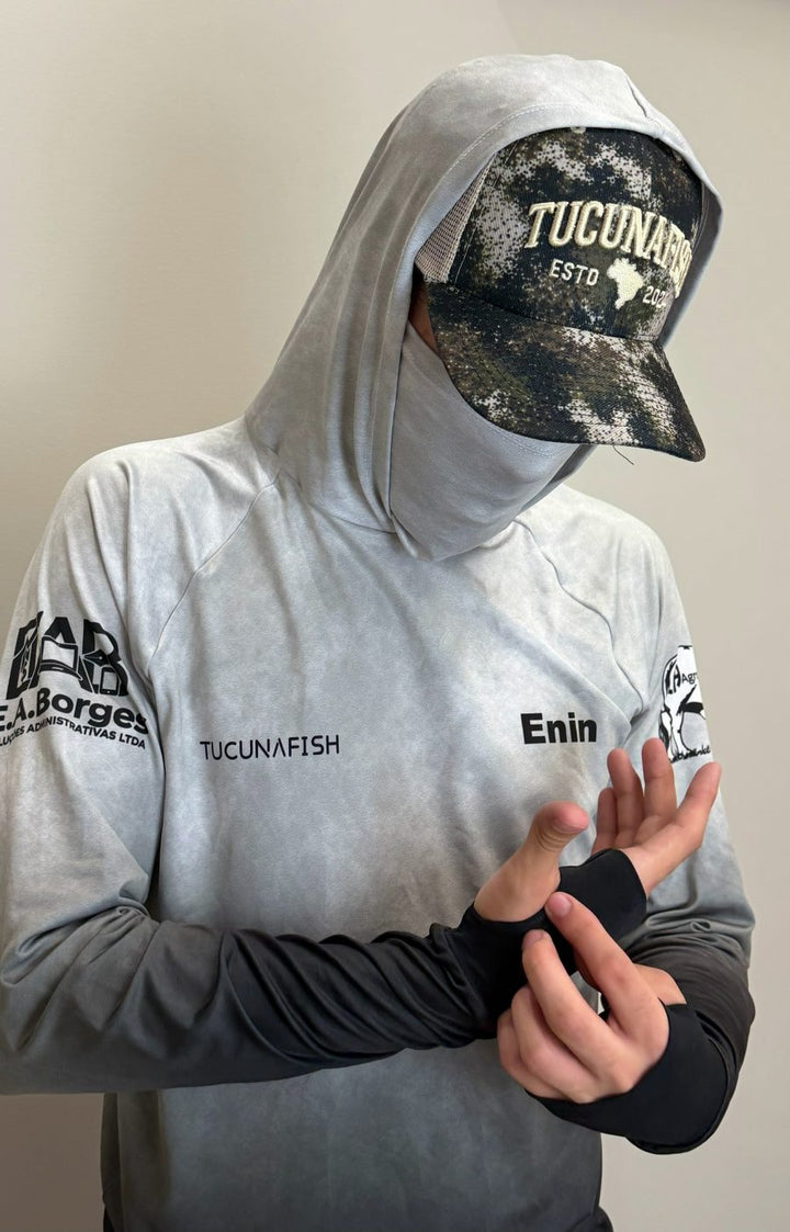 Pescador vestindo camisa de pesca TucunaFish com capuz, bandana integrada e luvinha, personalizada com nome e logos nas mangas